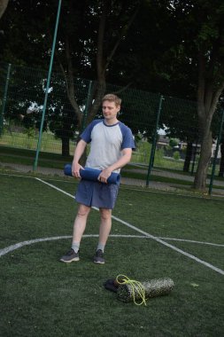 Spor giyim sektöründe genç bir adam sabah spor sahasında spor aleti kullanarak spor yapıyor. Forma olan bağlılığı odaklanma ve enerjiyle eğitim rutinini gerçekleştiriyor.