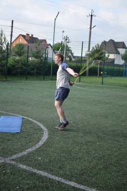 Spor giyim sektöründe genç bir adam sabah spor sahasında spor aleti kullanarak spor yapıyor. Forma olan bağlılığı odaklanma ve enerjiyle eğitim rutinini gerçekleştiriyor.