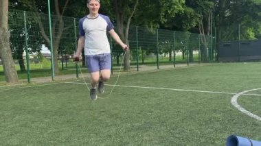 Spor giyim sektöründe genç bir adam sabah spor sahasında spor aleti kullanarak spor yapıyor. Forma olan bağlılığı odaklanma ve enerjiyle eğitim rutinini gerçekleştiriyor.