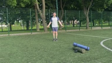 Spor giyim sektöründe genç bir adam sabah spor sahasında spor aleti kullanarak spor yapıyor. Forma olan bağlılığı odaklanma ve enerjiyle eğitim rutinini gerçekleştiriyor.