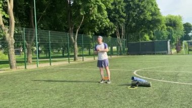 Spor giyim sektöründe genç bir adam sabah spor sahasında spor aleti kullanarak spor yapıyor. Forma olan bağlılığı odaklanma ve enerjiyle eğitim rutinini gerçekleştiriyor.