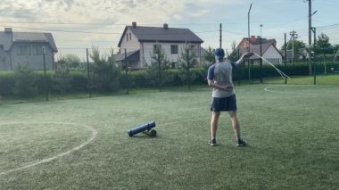 Spor giyim sektöründe genç bir adam sabah spor sahasında spor aleti kullanarak spor yapıyor. Forma olan bağlılığı odaklanma ve enerjiyle eğitim rutinini gerçekleştiriyor.