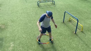 Spor giyimli genç bir adam spor yapıyor, spor aletini sabahları spor salonunda fiziksel egzersiz için kullanıyor. Forma olan bağlılığı odaklanma ve enerjiyle eğitim rutinini gerçekleştiriyor.