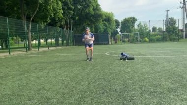 Spor giyim sektöründe genç bir adam sabah spor sahasında spor aleti kullanarak spor yapıyor. Forma olan bağlılığı odaklanma ve enerjiyle eğitim rutinini gerçekleştiriyor.