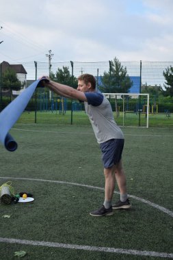 Spor giyim sektöründe genç bir adam sabah spor sahasında spor aleti kullanarak spor yapıyor. Forma olan bağlılığı odaklanma ve enerjiyle eğitim rutinini gerçekleştiriyor.