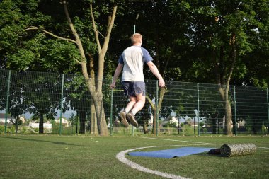 Spor giyim sektöründe genç bir adam sabah spor sahasında spor aleti kullanarak spor yapıyor. Forma olan bağlılığı odaklanma ve enerjiyle eğitim rutinini gerçekleştiriyor.