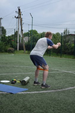 Spor giyim sektöründe genç bir adam sabah spor sahasında spor aleti kullanarak spor yapıyor. Forma olan bağlılığı odaklanma ve enerjiyle eğitim rutinini gerçekleştiriyor.