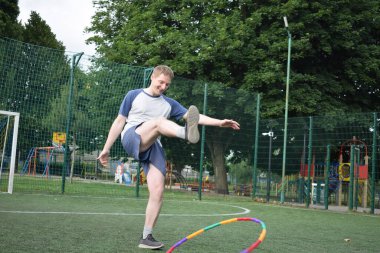 Spor giyim sektöründe genç bir adam sabah spor sahasında spor aleti kullanarak spor yapıyor. Forma olan bağlılığı odaklanma ve enerjiyle eğitim rutinini gerçekleştiriyor.