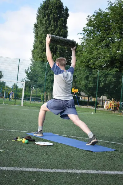 Spor giyim sektöründe genç bir adam sabah spor sahasında spor aleti kullanarak spor yapıyor. Forma olan bağlılığı odaklanma ve enerjiyle eğitim rutinini gerçekleştiriyor.