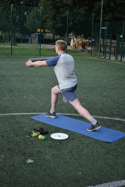 Spor giyim sektöründe genç bir adam sabah spor sahasında spor aleti kullanarak spor yapıyor. Forma olan bağlılığı odaklanma ve enerjiyle eğitim rutinini gerçekleştiriyor.