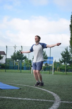 Spor giyim sektöründe genç bir adam sabah spor sahasında spor aleti kullanarak spor yapıyor. Forma olan bağlılığı odaklanma ve enerjiyle eğitim rutinini gerçekleştiriyor.