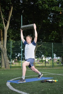 Spor giyim sektöründe genç bir adam sabah spor sahasında spor aleti kullanarak spor yapıyor. Forma olan bağlılığı odaklanma ve enerjiyle eğitim rutinini gerçekleştiriyor.