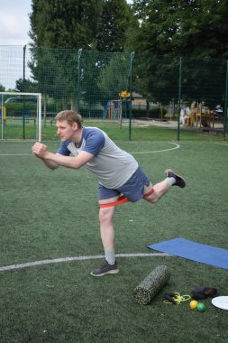 Spor giyim sektöründe genç bir adam sabah spor sahasında spor aleti kullanarak spor yapıyor. Forma olan bağlılığı odaklanma ve enerjiyle eğitim rutinini gerçekleştiriyor.