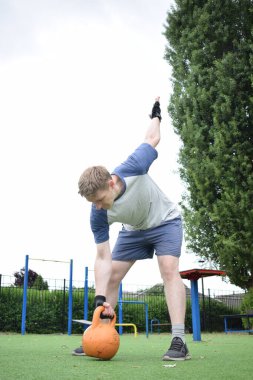 Spor giyim sektöründe genç bir adam sabah spor sahasında spor aleti kullanarak spor yapıyor. Forma olan bağlılığı odaklanma ve enerjiyle eğitim rutinini gerçekleştiriyor.