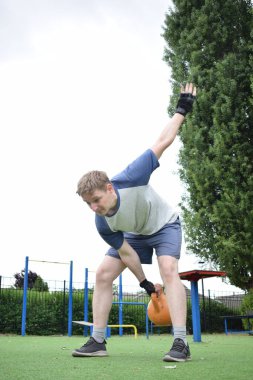 Spor giyim sektöründe genç bir adam sabah spor sahasında spor aleti kullanarak spor yapıyor. Forma olan bağlılığı odaklanma ve enerjiyle eğitim rutinini gerçekleştiriyor.