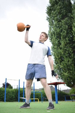 Spor giyim sektöründe genç bir adam sabah spor sahasında spor aleti kullanarak spor yapıyor. Forma olan bağlılığı odaklanma ve enerjiyle eğitim rutinini gerçekleştiriyor.