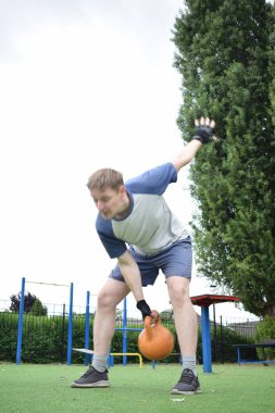 Spor giyim sektöründe genç bir adam sabah spor sahasında spor aleti kullanarak spor yapıyor. Forma olan bağlılığı odaklanma ve enerjiyle eğitim rutinini gerçekleştiriyor.