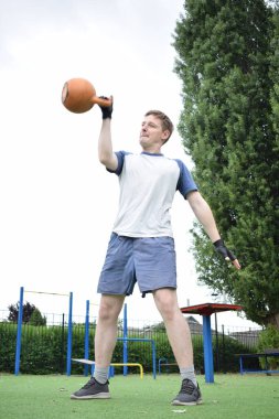 Spor giyim sektöründe genç bir adam sabah spor sahasında spor aleti kullanarak spor yapıyor. Forma olan bağlılığı odaklanma ve enerjiyle eğitim rutinini gerçekleştiriyor.