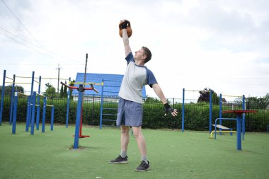 Spor giyim sektöründe genç bir adam sabah spor sahasında spor aleti kullanarak spor yapıyor. Forma olan bağlılığı odaklanma ve enerjiyle eğitim rutinini gerçekleştiriyor.