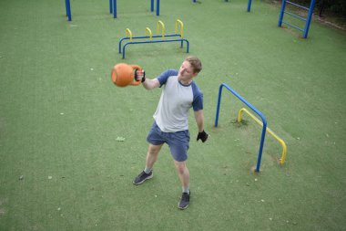 Spor giyim sektöründe genç bir adam sabah spor sahasında spor aleti kullanarak spor yapıyor. Forma olan bağlılığı odaklanma ve enerjiyle eğitim rutinini gerçekleştiriyor.