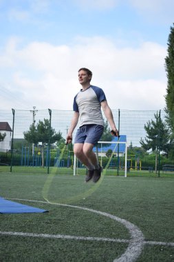 Spor giyim sektöründe genç bir adam sabah spor sahasında spor aleti kullanarak spor yapıyor. Forma olan bağlılığı odaklanma ve enerjiyle eğitim rutinini gerçekleştiriyor.