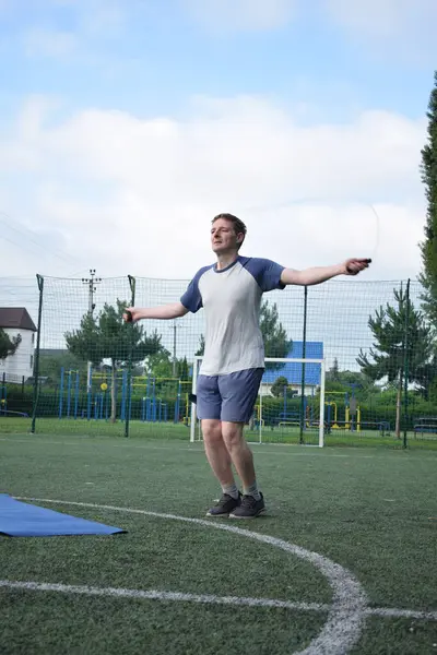 Spor giyim sektöründe genç bir adam sabah spor sahasında spor aleti kullanarak spor yapıyor. Forma olan bağlılığı odaklanma ve enerjiyle eğitim rutinini gerçekleştiriyor.