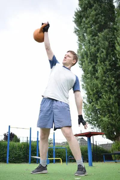 Spor giyim sektöründe genç bir adam sabah spor sahasında spor aleti kullanarak spor yapıyor. Forma olan bağlılığı odaklanma ve enerjiyle eğitim rutinini gerçekleştiriyor.