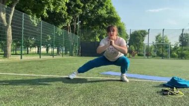 Odaklanmış genç bir bayan atlet dinamik bir şekilde ısınma egzersizleri yapıyor ve dışarıda esniyor. Spor giyim sektöründe bedenini düzenli bir rutin içinde fiziksel taleplere özenle hazırlar.
