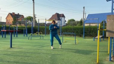 Odaklanmış genç bir bayan atlet dinamik bir şekilde ısınma egzersizleri yapıyor ve dışarıda esniyor. Spor giyim sektöründe bedenini düzenli bir rutin içinde fiziksel taleplere özenle hazırlar.