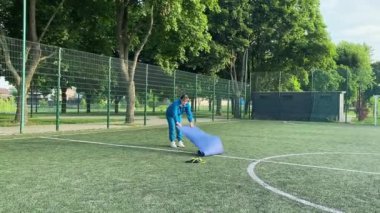 Odaklanmış genç bir bayan atlet dinamik bir şekilde ısınma egzersizleri yapıyor ve dışarıda esniyor. Spor giyim sektöründe bedenini düzenli bir rutin içinde fiziksel taleplere özenle hazırlar.