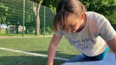 Odaklanmış genç bir bayan atlet dinamik bir şekilde ısınma egzersizleri yapıyor ve dışarıda esniyor. Spor giyim sektöründe bedenini düzenli bir rutin içinde fiziksel taleplere özenle hazırlar.