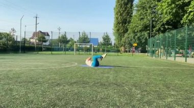 Odaklanmış genç bir bayan atlet dinamik bir şekilde ısınma egzersizleri yapıyor ve dışarıda esniyor. Spor giyim sektöründe bedenini düzenli bir rutin içinde fiziksel taleplere özenle hazırlar.