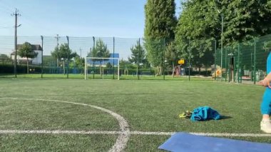 Odaklanmış genç bir bayan atlet dinamik bir şekilde ısınma egzersizleri yapıyor ve dışarıda esniyor. Spor giyim sektöründe bedenini düzenli bir rutin içinde fiziksel taleplere özenle hazırlar.