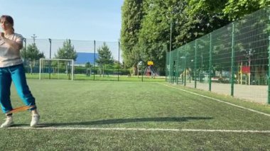 Odaklanmış genç bir bayan atlet dinamik bir şekilde ısınma egzersizleri yapıyor ve dışarıda esniyor. Spor giyim sektöründe bedenini düzenli bir rutin içinde fiziksel taleplere özenle hazırlar.