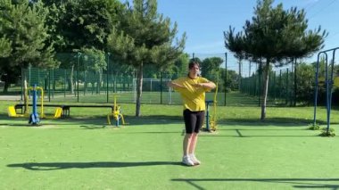 Spor giyim sektöründe genç bir kadın spor yapıyor, spor aletini sabahları spor sahasında fiziksel egzersiz için kullanıyor. Forma olan bağlılığı odaklanma ve enerjiyle eğitim rutinini gerçekleştiriyor.