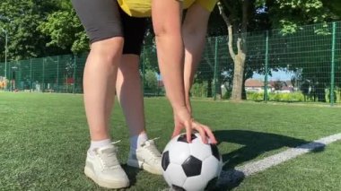 Spor giyimli genç bir kadın sabah futbol sahasında antrenman yapıyor. Spor için adanmışlık ve tutku, sabah egzersizinin özü ve açık havada pratik.