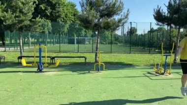 Spor giyim sektöründe genç bir kadın spor yapıyor, spor aletini sabahları spor sahasında fiziksel egzersiz için kullanıyor. Forma olan bağlılığı odaklanma ve enerjiyle eğitim rutinini gerçekleştiriyor.
