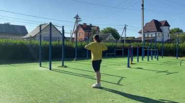 Spor giyim sektöründe genç bir kadın spor yapıyor, spor aletini sabahları spor sahasında fiziksel egzersiz için kullanıyor. Forma olan bağlılığı odaklanma ve enerjiyle eğitim rutinini gerçekleştiriyor.