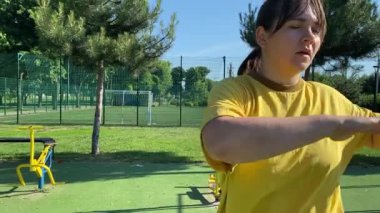 Spor giyim sektöründe genç bir kadın spor yapıyor, spor aletini sabahları spor sahasında fiziksel egzersiz için kullanıyor. Forma olan bağlılığı odaklanma ve enerjiyle eğitim rutinini gerçekleştiriyor.