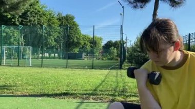 Spor giyim sektöründe genç bir kadın spor yapıyor, spor aletini sabahları spor sahasında fiziksel egzersiz için kullanıyor. Forma olan bağlılığı odaklanma ve enerjiyle eğitim rutinini gerçekleştiriyor.