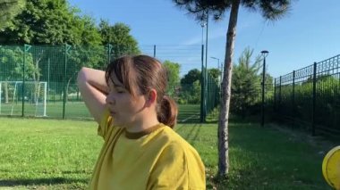 Spor giyim sektöründe genç bir kadın spor yapıyor, spor aletini sabahları spor sahasında fiziksel egzersiz için kullanıyor. Forma olan bağlılığı odaklanma ve enerjiyle eğitim rutinini gerçekleştiriyor.