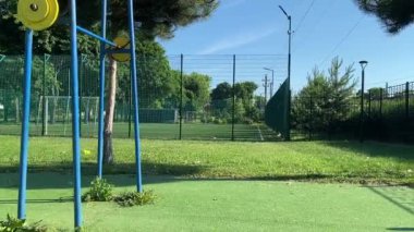 Spor giyim sektöründe genç bir kadın spor yapıyor, spor aletini sabahları spor sahasında fiziksel egzersiz için kullanıyor. Forma olan bağlılığı odaklanma ve enerjiyle eğitim rutinini gerçekleştiriyor.