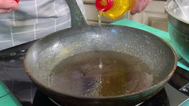 Önlüklü genç bir adam ev mutfağında tavada gözleme pişiriyor. Krepleri ustalıkla çeviriyor ve mükemmel pişirmelerini sağlıyor. Ev yemeği ve aşçılık tutkusu