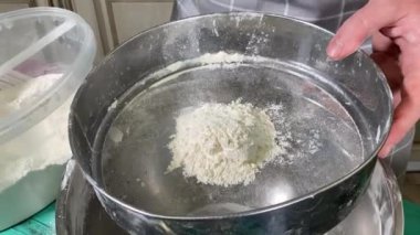 Önlüklü genç bir adam ev mutfağında yemek hazırlıyor, evde krep hazırlıyor. İçindekileri dikkatlice karıştırıyor, yemeği pişirmeye hazırlanıyor. Ev yemeği ve aşçılık becerileri.