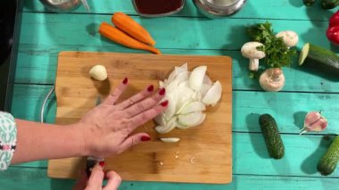 Mutfak konsepti, ev yapımı yemekler için hazırlama malzemeleri. Önlüklü genç bir kadın yemek pişiriyor, mutfak tezgahında sebze kesiyor. Ev yemeği ve gastronomi tutkusu.