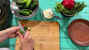 Mutfak konsepti, ev yapımı yemekler için hazırlama malzemeleri. Önlüklü genç bir kadın yemek pişiriyor, mutfak tezgahında sebze kesiyor. Ev yemeği ve gastronomi tutkusu.