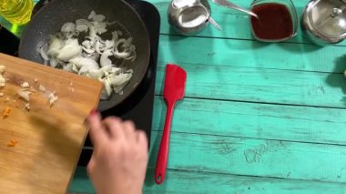 Mutfak konsepti, ev yapımı yemekler için hazırlama malzemeleri. Önlüklü, yemek pişiren genç ve güzel bir kadın mutfak tezgahında mirepoix yapıyor. Ev yemeği ve gastronomi tutkusu.