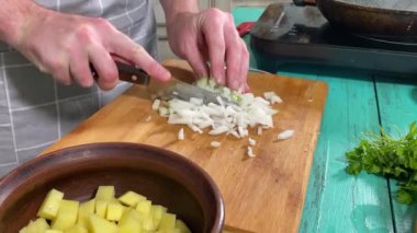 Mutfak konsepti, ev yapımı yemekler için hazırlama malzemeleri. Önlüklü genç bir adam ustalıkla yemek pişiriyor, mutfak tezgahında sebze doğruyor. Ev yemeği ve aşçılık tutkusu