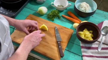 Mutfak konsepti, ev yapımı yemekler için hazırlama malzemeleri. Önlüklü genç bir adam ustalıkla yemek pişiriyor, mutfak tezgahında sebze doğruyor. Ev yemeği ve aşçılık tutkusu