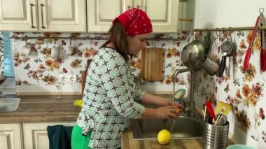 Mutfak konsepti, ev yapımı yemekler için hazırlama malzemeleri. Önlüklü genç bir kadın yemek pişiriyor, mutfak lavabosunda meyve yıkıyor. Ev yemeği ve gastronomi tutkusu.